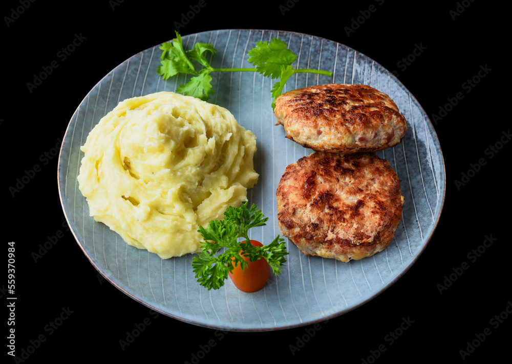 mashed potatoes with meat cutlets on a black background top view
