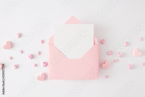 Valentines Day concept. Flat lay photo of pink heart shaped baubles on white background and envelope with letter in the middle. Lovers holiday card idea. © Goncharuk film