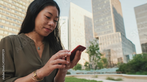 Close-up, Young girl uses smartphone while sitting on modern buildings background