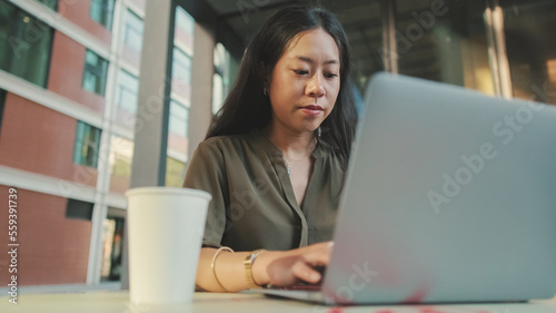 Young woman freelancer working on laptop and drinking coffee