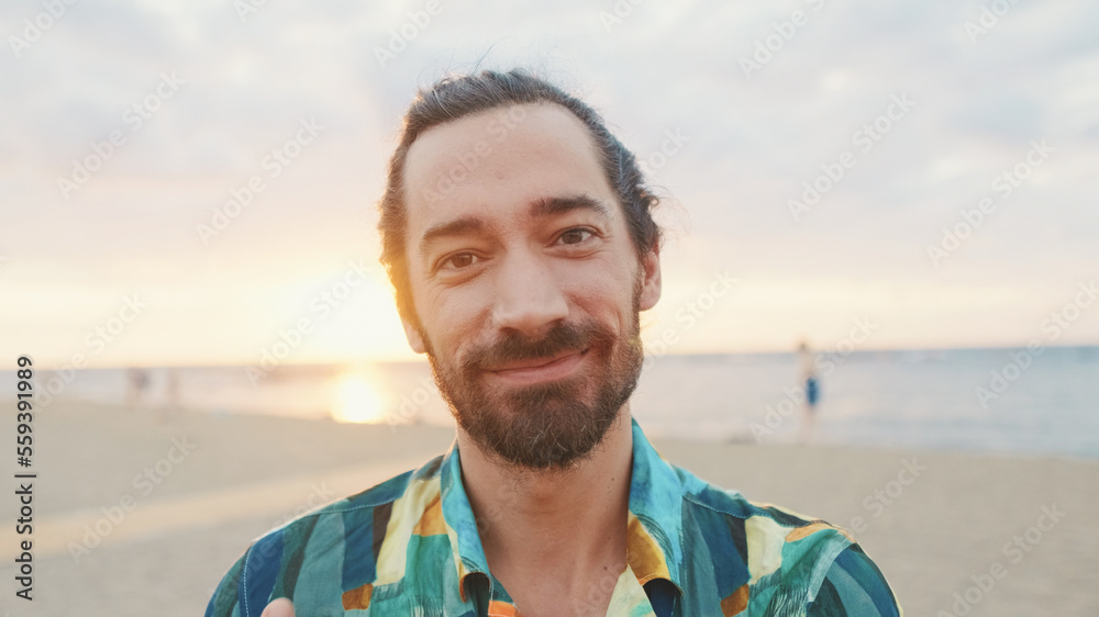 Close-up of young smiling man looking at the camera on the beach at sunrise Close-up of young smiling man looking at the camera on the beach at sunrise