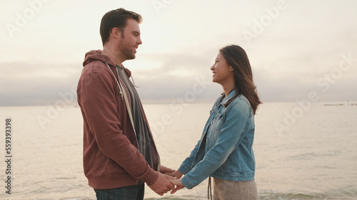 Man and woman hold hands and look at each other on the seascape