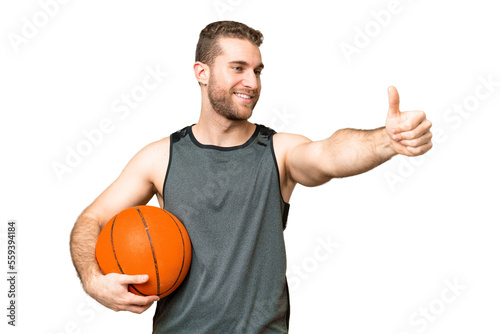 Handsome young man playing basketball over isolated chroma key background giving a thumbs up gesture