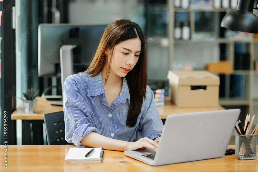beautiful woman typing on tablet and laptop while sitting at the working wooden table modern office. beautiful woman typing on tablet and laptop while sitting at the working wooden table modern office.