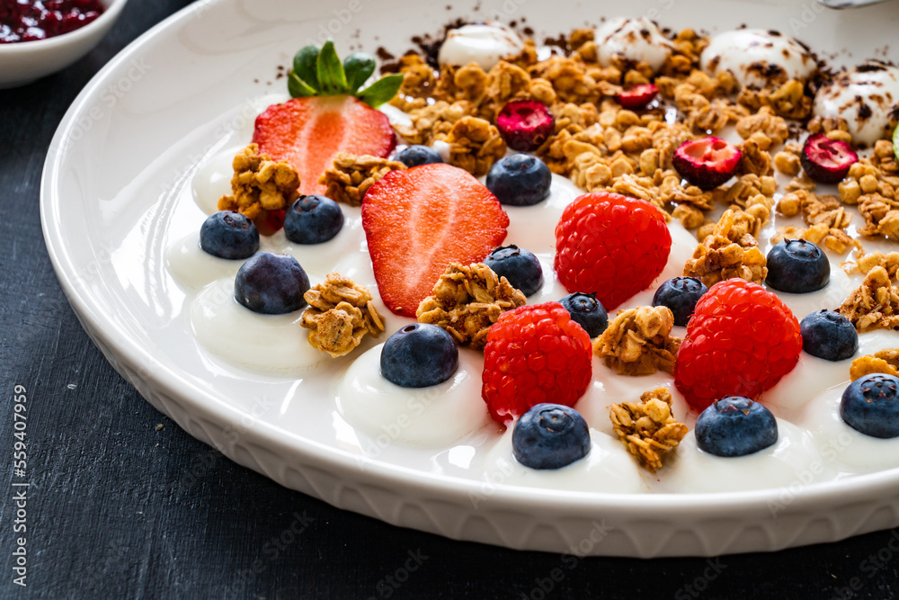 Yogurt with strawberries, blueberries, raspberries and muesli in bowl on wooden table
Yogurt with strawberries, blueberries, raspberries and muesli in bowl on wooden table