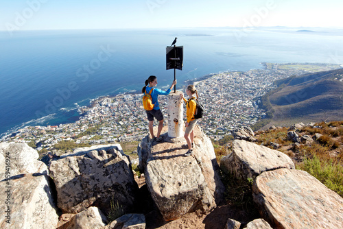 Two women are standing on top of Lion's Head and looking down at the city of Cape Town. South Africa. photo