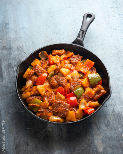 Sweet and Sour Pork with bell pepper, pineapple in iron cast pan