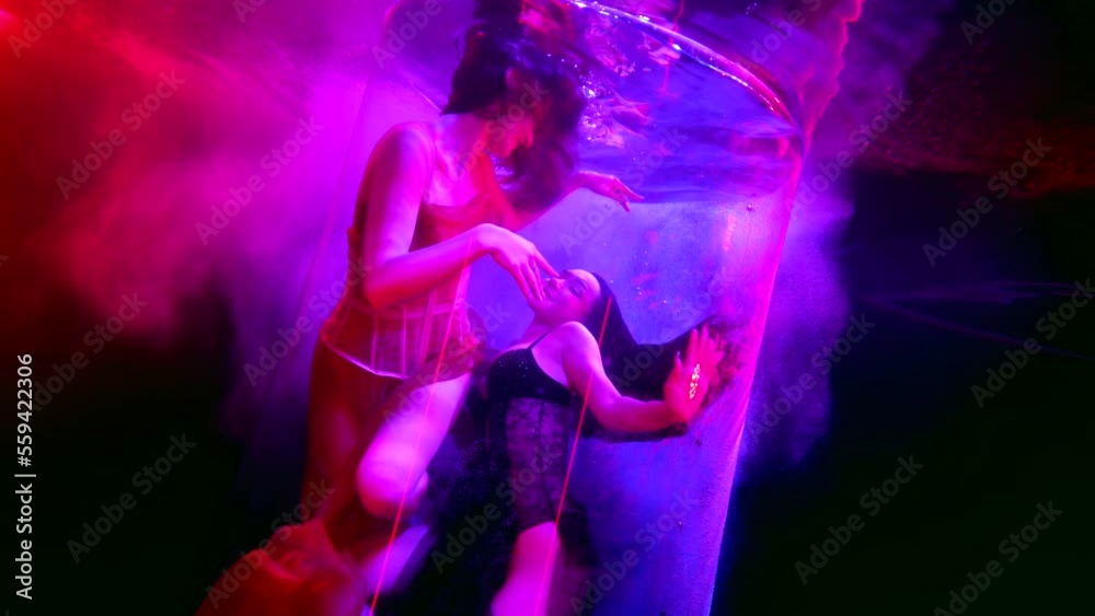 angel and demon underwater, two beautiful sexy women swimming together in pool with