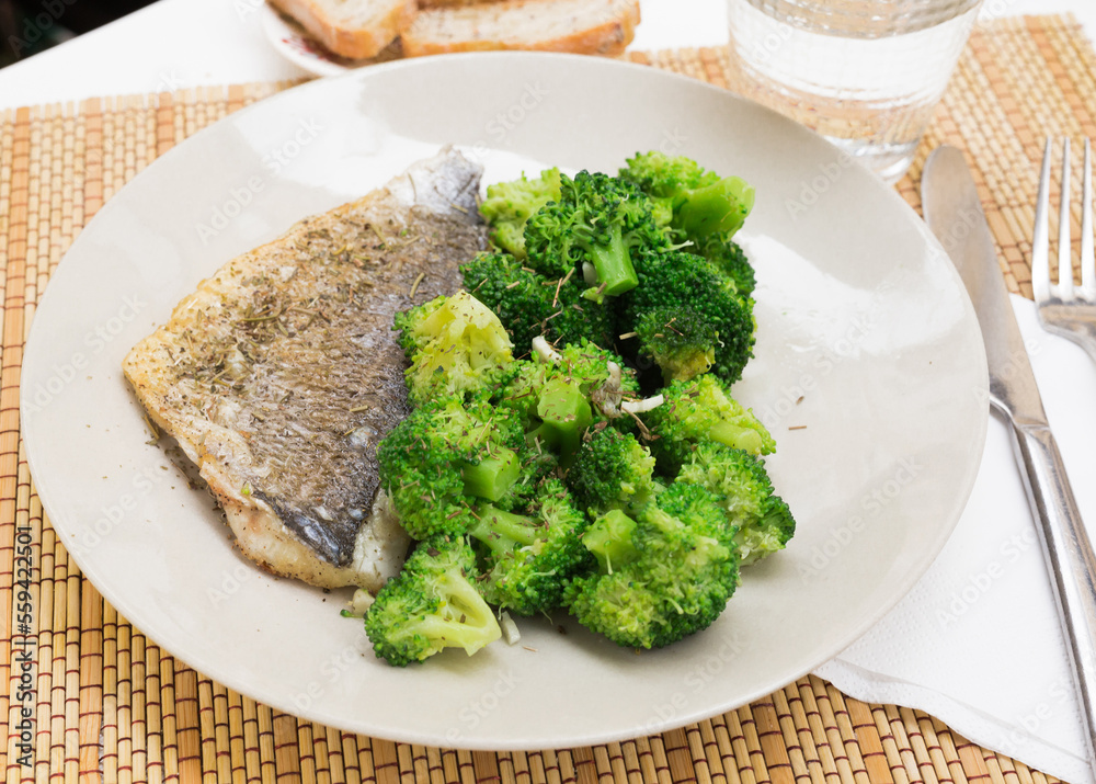 dish of fried dorado fish fillet with boiled broccoli