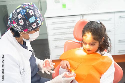 dentist teaching a girl how to brush her teeth in a dental clinic