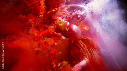 sexy half-naked woman swimming in pool or aquarium, doing somersault in water with maple leaves