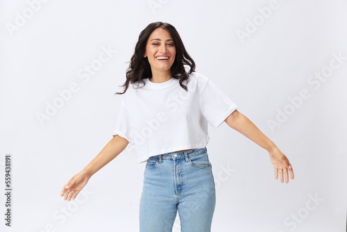Woman in white t-shirt on white background brunette hands up gestures and signals poses in jeans emotion, lifestyle smiles, copy space