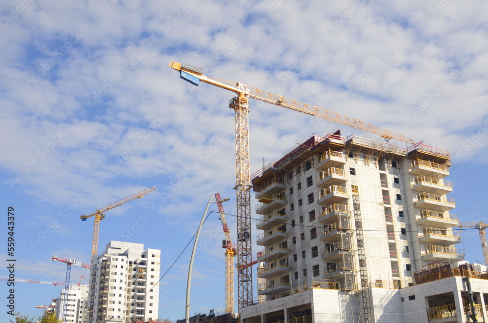 A construction site, a white building and a tall construction crane. Developers industry. Buying a home, mortgage. Modern residential buildings. Space for text, blue sky, summer A construction site, a white building and a tall construction crane. Developers industry. Buying a home, mortgage. Modern residential buildings. Space for text, blue sky, summer