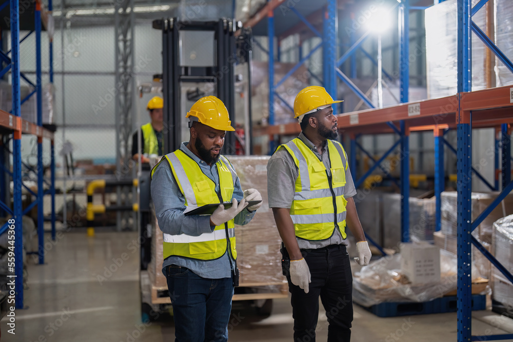 African american working in warehouse hold stock check list while truck loading carton box near by African american working in warehouse hold stock check list while truck loading carton box near by