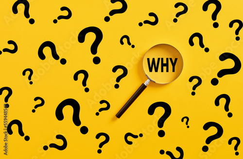 Searching for information, data, solution or answer. Magnifying glass magnifies the word why and question mark signs on yellow background. photo
