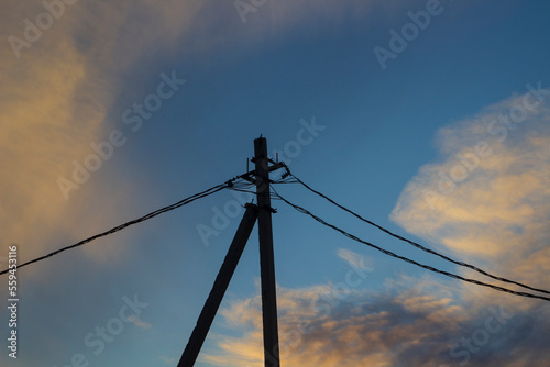 Electricity pylon with cables against sunset sky