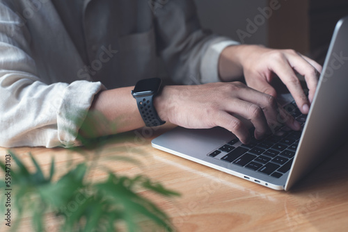 Business man working on laptop computer, typing on laptop keyboard on office table, surfing the internet, online job, online study, e-learning, working at home, telecommuting concept