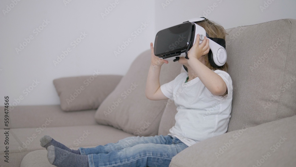 Little child sit on sofa discover new world with virtual reality glasses, modern Little child sit on sofa discover new world with virtual reality glasses, modern