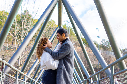 Young couple hugging looking at each other tenderly. Young interracial couple looking each other.