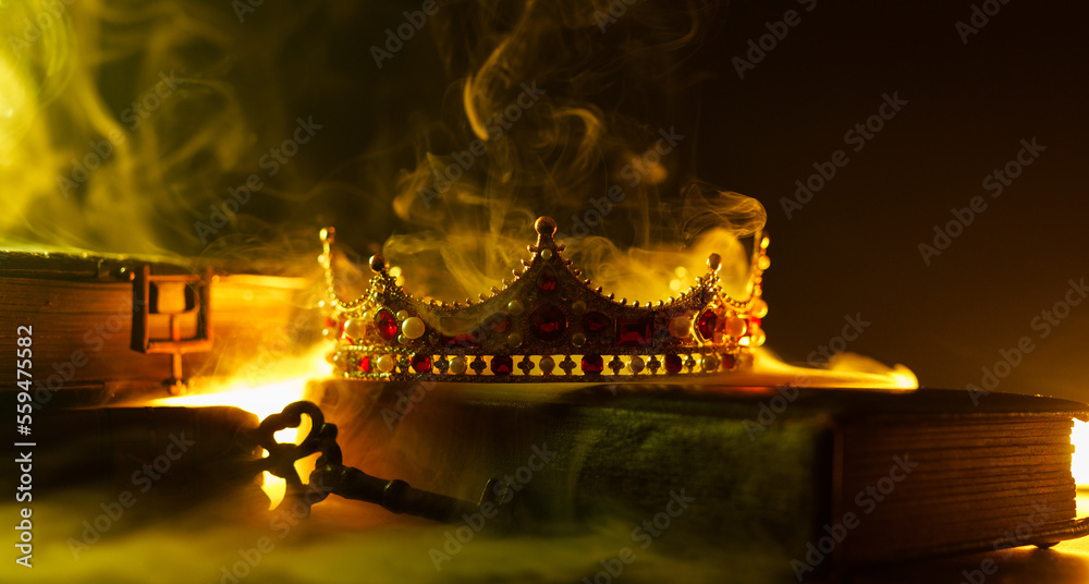 Fototapeta premium A golden crown, an old book, a key and old casket on a dark background. Panoramic view of the fog. Layout for your logo. A horizontal banner with a place to copy the cover image of a popular website.