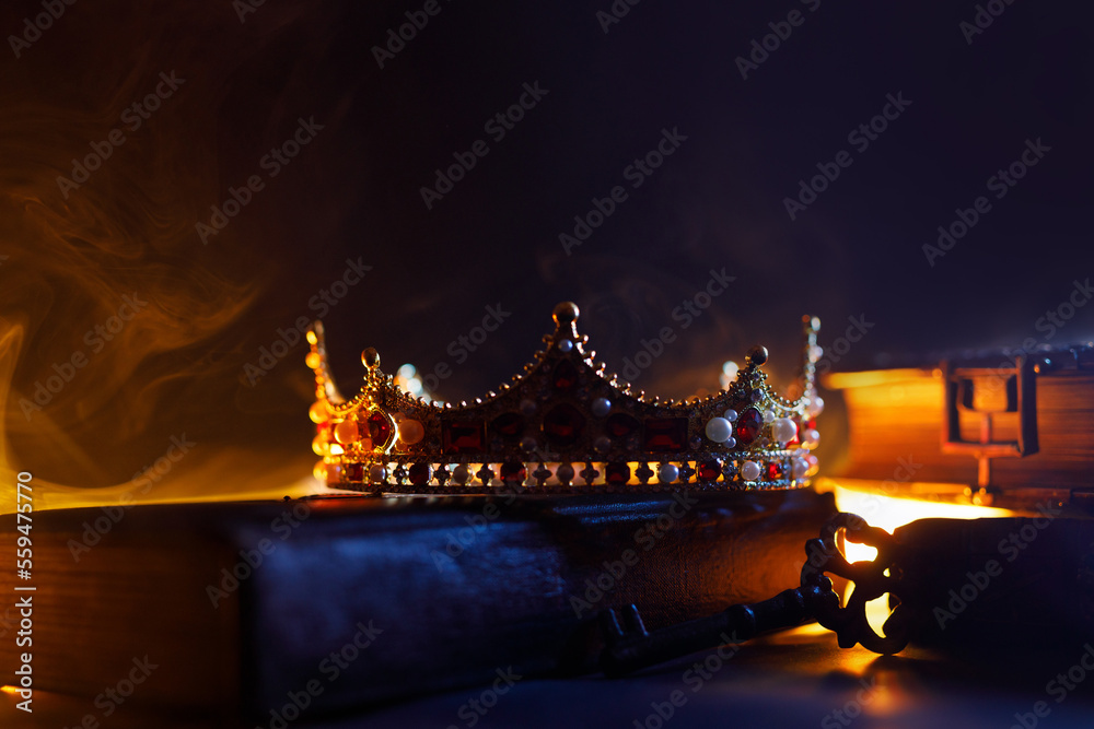 Fototapeta premium A golden crown, an old book, a key and old casket on a dark background. Panoramic view of the fog. Layout for your logo. A horizontal banner with a place to copy the cover image of a popular website.