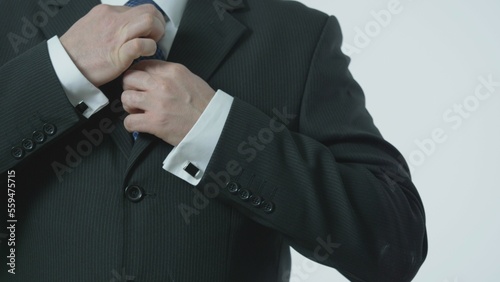 Detail of man hands closes his buttons on his suit, arrange tie