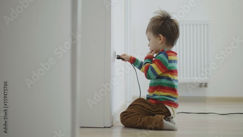 Little child connecting the electrical device plugging it into the wall socket