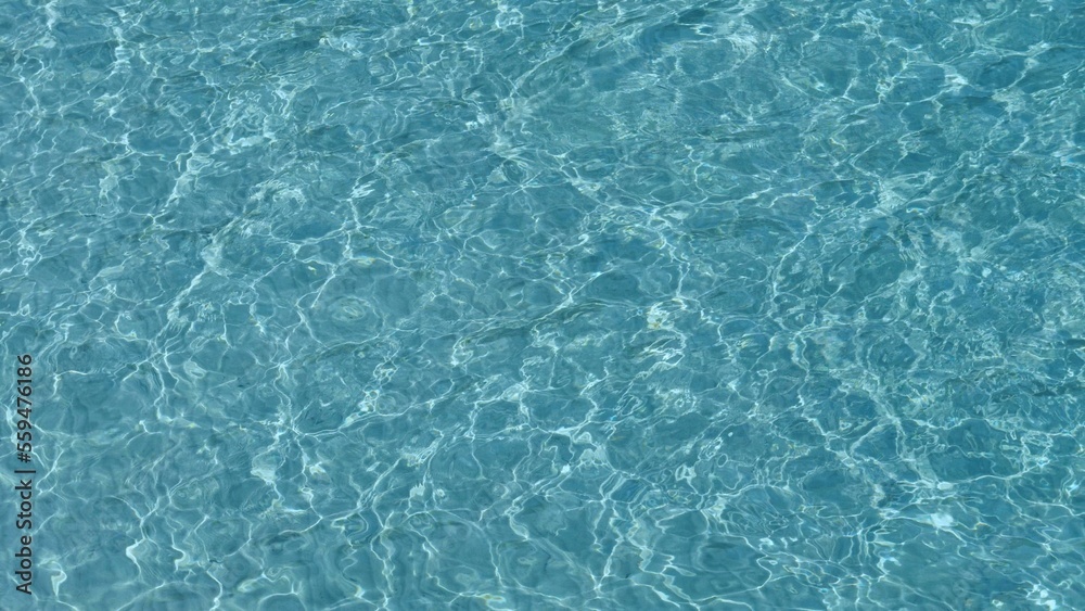 Abstract shapes of shallow blue clear sea water ripples on white fine beach sand