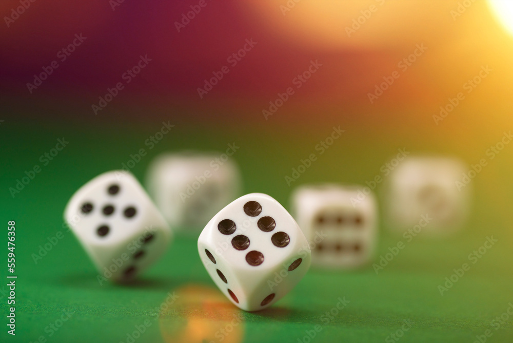White dice on a green felt table with bokeh background White dice on a green felt table with bokeh background