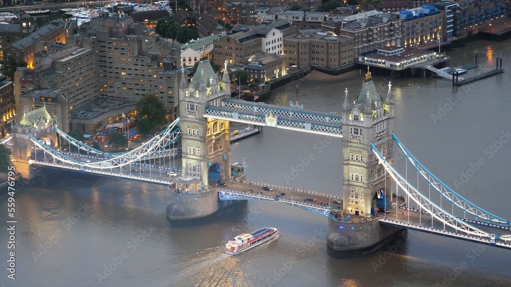 Top view aerial panorama of city lights at sunset dusk and ship navigation on Thames River under the Tower Bridge in London