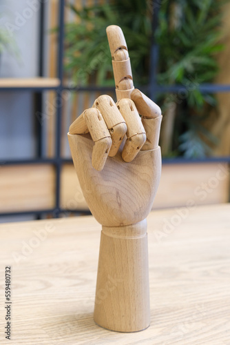 Wooden model of a human hand on a desk. Model of a human hand with the index finger raised up. Wooden hand with index finger extended. Concept of communication.