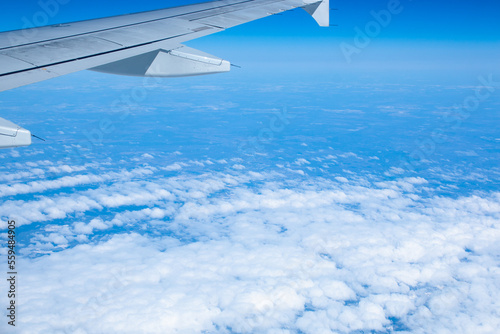 Wing of an airplane flying over white clouds and blue sky