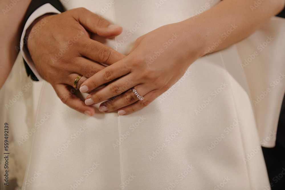 Couple holding hands on bride's belly Couple holding hands on bride's belly