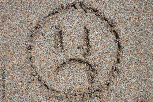 sad emoticon on beach sand