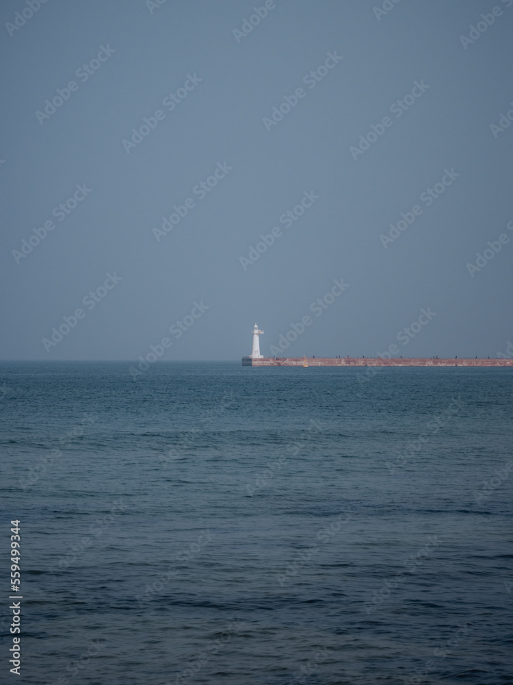 A white lighthouse standing alone in the middle of the ocean