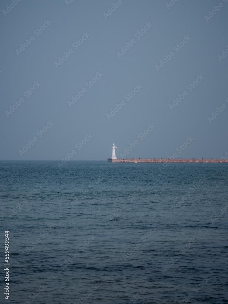 A white lighthouse standing alone in the middle of the ocean A white lighthouse standing alone in the middle of the ocean