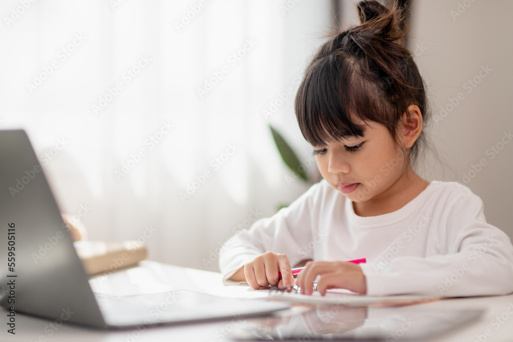 Asian schoolgirl doing her homework with laptop at home. Children use gadgets to study. Education and distance learning for kids. Homeschooling during quarantine. Stay at home Asian schoolgirl doing her homework with laptop at home. Children use gadgets to study. Education and distance learning for kids. Homeschooling during quarantine. Stay at home
