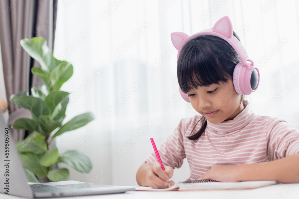 Asian little girl in headphones have video call distant class with teacher using laptop, study online on computer, homeschooling concept Asian little girl in headphones have video call distant class with teacher using laptop, study online on computer, homeschooling concept