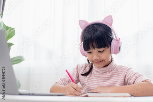 Asian little girl in headphones have video call distant class with teacher using laptop, study online on computer, homeschooling concept