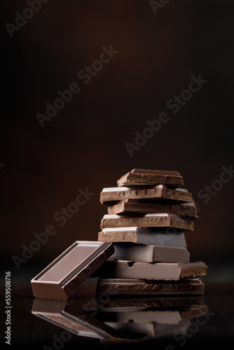 Broken chocolate pieces on dark background. Stack of dark chocolate. Chocolate concept