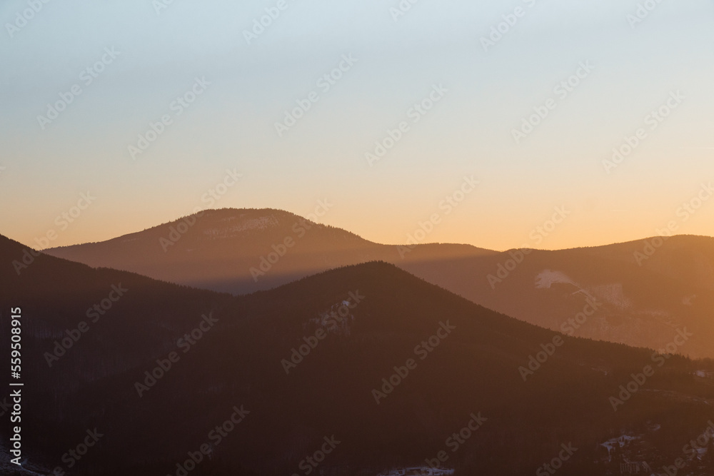 Last rays of the sun illuminating the mountainsides with orange light. Ostravice, Beskydy mountains, Ostrava