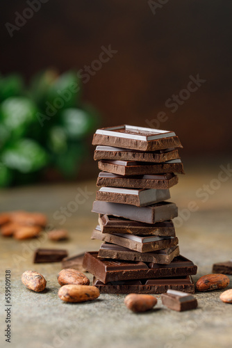 Broken chocolate pieces on dark background. Stack of dark chocolate. Chocolate concept