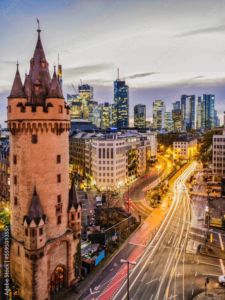Vertical shot of Eschenheim Tower, old and new Frankfurt city buildings illuminated at night