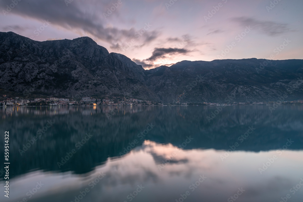 View of kotor bay, beautiful reflection with blue cloudy sky and boats and houses on shore