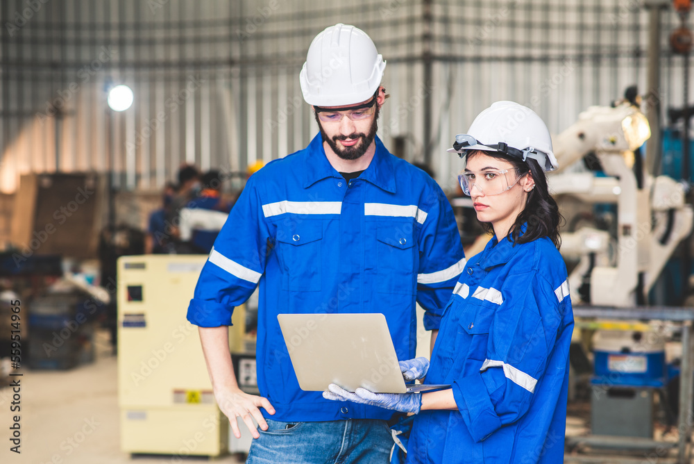 Engineers team mechanic using computer controller Robotic arm for welding steel in steel factory workshop. Industry robot programming software for automated manufacturing technology