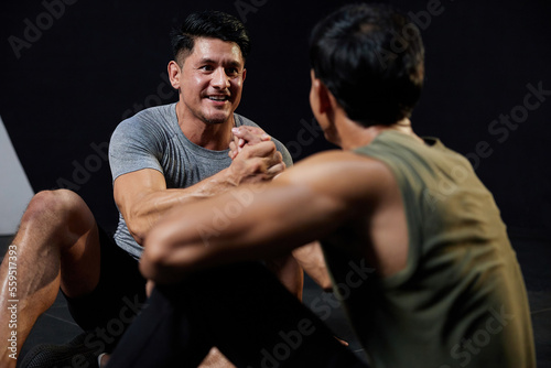 young athletic men meeting in the gym and shaking hands after workout