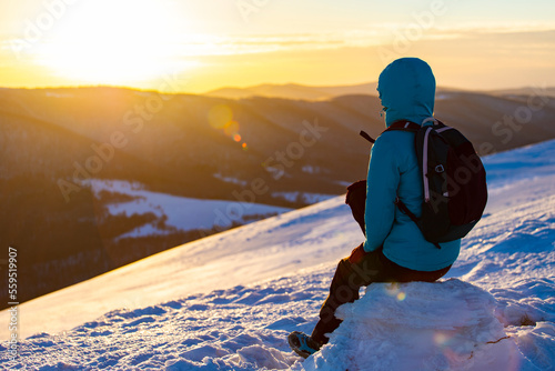 backpacker girl admires panorama of snowy mountains from the summit at sunset, hiking on snowy ridge in Bieszczady mountains, polonina carynska photo