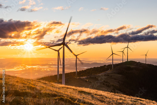 A group of wind mills on a mountain ridge in front of a morning sky