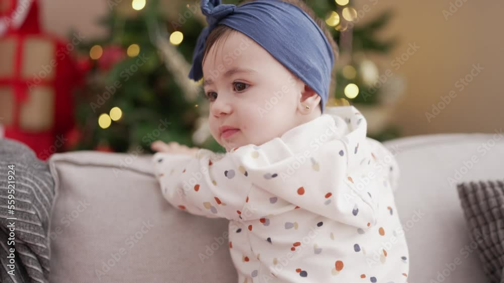 Adorable toddler smiling confident standing on sofa by christmas tree at home Adorable toddler smiling confident standing on sofa by christmas tree at home