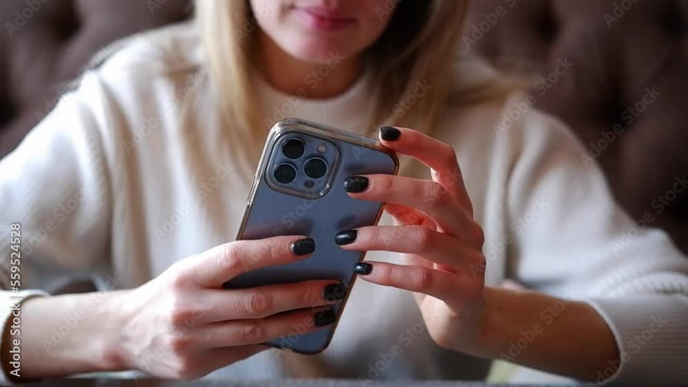 Woman hand is holding and touching iphone 13 pro and looking at the screen of mobile phone in light room. Woman hand is holding and touching iphone 13 pro and looking at the screen of mobile phone in light room.
